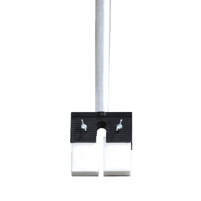 Close-up view of the base of a metal pole secured by a clamp above two white blocks on the floor with partial view of a persons feet in the background.